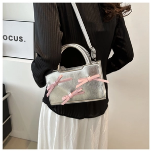 Detail of silver metallic handbag featuring pink silk bows on a model back view