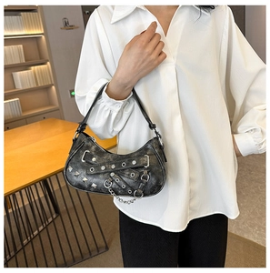 Detail of black punk shoulder bag with silver rivets, metal chains, and distressed PU leather