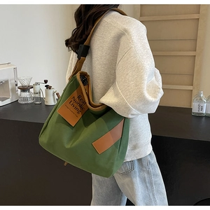 Green canvas tote bag with brown straps shown in a modern lifestyle lifestyle setting