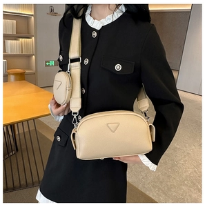Detail of beige textured leather crossbody bag with round coin purse and wide fabric strap