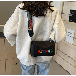 Détail du sac bandoulière en nylon noir avec broderie SJCHAO colorée et sangle tissée