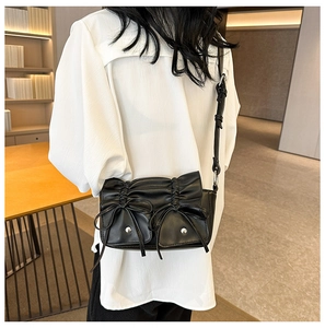 Close-up of black PU leather crossbody bag with pleated details and stylish bow accents