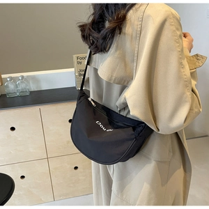 Détail du sac bandoulière noir en nylon en demi-lune avec impression de lettres blanches