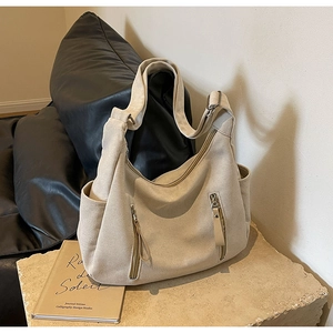Chic beige canvas hobo crossbody bag with dual vertical zipper pockets on stone base