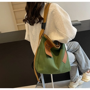 Detail of green canvas tote bag with brown fabric strap and chic leather brand tag