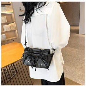 Detail view of black pleated PU leather crossbody bag with stylish bow and pocket details