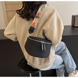 Vue détaillée d'un sac bandoulière noir en nylon doté d'une large sangle à motifs colorés