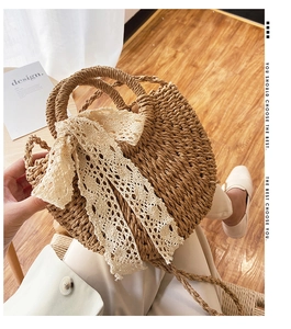 Detail of woven straw handbag featuring a large lace bow and circular top handles