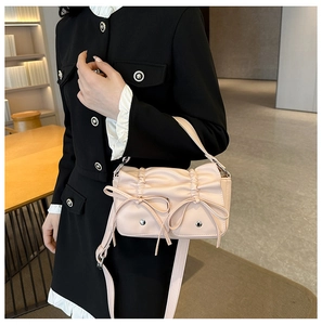 Detail of light pink wrinkled leather handbag with elegant bows and metallic rivets