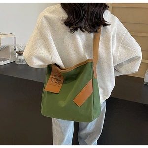 Detailed shot of retro green canvas shoulder bag featuring brown leather straps and Nordic tag