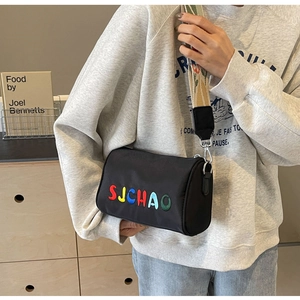 Détail du sac bandoulière cylindrique noir avec broderie et sangle à fleurs