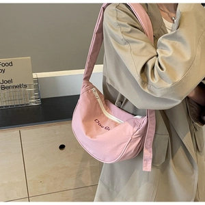 Sac bandoulière rose en forme de croissant avec broderie porté par un mannequin chic