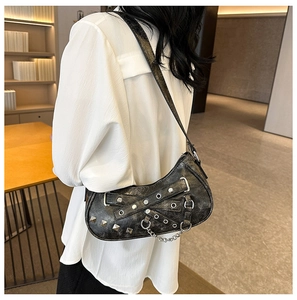 Detail view of retro punk style shoulder bag featuring metal eyelets and decorative chain