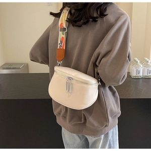 Détail du sac bandoulière beige avec double fermeture éclair argentée et sangle tissée à motifs