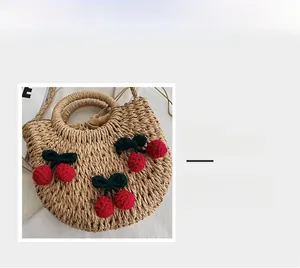 Detail magnification of woven straw handbag featuring red knitted cherry decorations