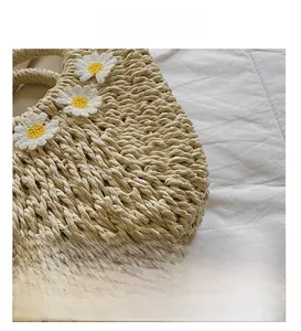 Detail view of woven straw bag featuring handcrafted white daisy floral embellishments