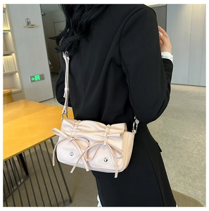 Detailed view of apricot pink PU shoulder bag with pleated design and ribbon bows