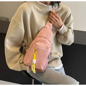 Detail view of pink nylon crossbody bag with floral embroidery strap and yellow charm