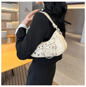 Detailed close-up of cream white saddle bag with silver rivets and metallic chain strap