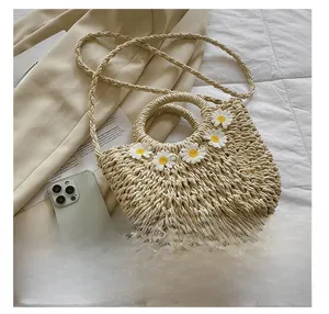 Detail view of beige woven straw handbag with white daisy appliqués and strap