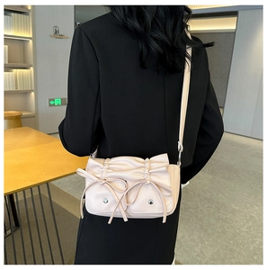 Detail of light pink PU leather bag with pleated bow design on a black blazer