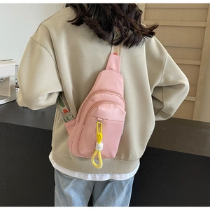 Pink nylon crossbody bag detail with double zippers and colorful woven shoulder strap
