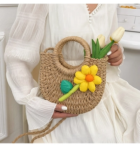Vue détaillée du sac à main en paille tressée avec une grande fleur jaune et feuilles vertes