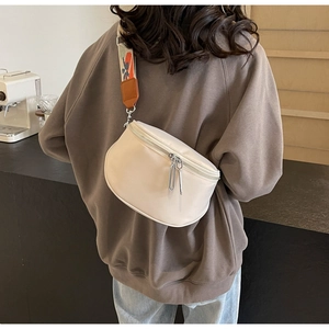 Détail du sac bandoulière demi-lune crème avec large sangle tissée sur modèle