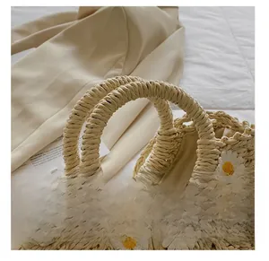 Detail shot of woven straw handbag featuring delicate daisy embroidery and rounded handles