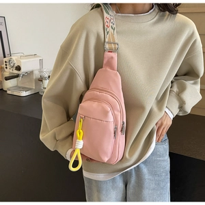 Pink nylon crossbody bag detail with floral embroidered strap and layered zipper design