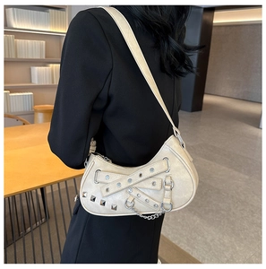 Detail shot of beige PU crescent shoulder bag with punk rivets and metal eyelet straps