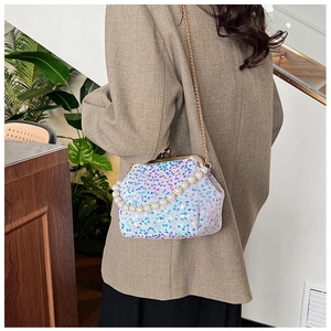 Detail of sequin evening bag with large pearl handle and golden chain strap for women