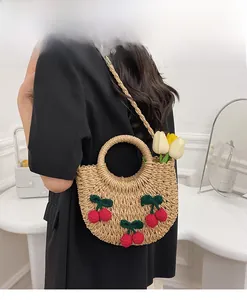 Detail of woven straw bag featuring 3D knitted cherries and floral tulip decoration