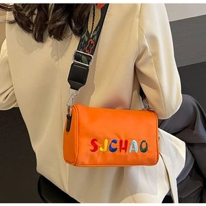 Détail du sac bandoulière en toile orange avec broderie et large sangle imprimée