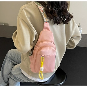 Pink nylon crossbody bag detail with floral embroidered strap and yellow cord pendant