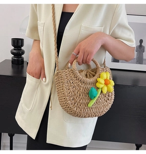 Détail du sac à bandoulière en paille tressée avec broderie tournesol jaune et poignée