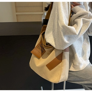 Detail showing the brown PU leather wide shoulder strap and beige canvas material of the bag