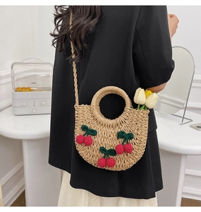 Detailed close-up of handmade woven crescent bag with decorative crochet cherry accents