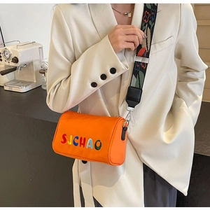 Détail du sac bandoulière cylindrique orange avec broderie et sangle florale large