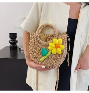 Détail d'un sac en paille tressée orné d'une grande fleur de tournesol jaune et feuilles