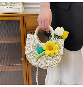 Détail d'un sac demi-lune beige tissé à la main avec breloque tournesol et bandoulière tressée