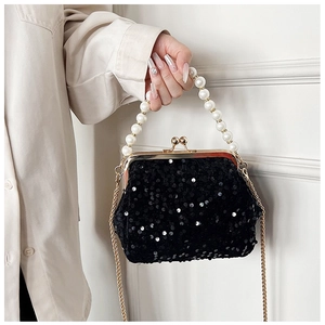 Detailed view of black sequin evening bag with pearl handle and golden clasp closure