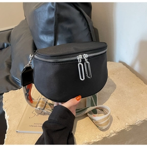 Sac bandoulière demi-lune en nylon noir minimaliste avec sangle tissée colorée sur socle