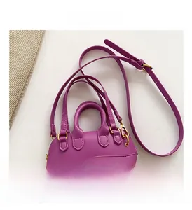Flat lay of purple PU leather crossbody bag with top handles and gold accessories