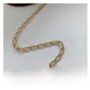 Detailaufnahme der goldenen Metallkette mit polierten ovalen Gliedern auf weißem Stoff