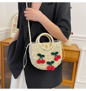 Detail view of woven straw bag with cherry embroidery and drawstring lining close-up