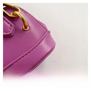 Macro shot of magenta lychee grain leather handbag with premium gold metal hook details