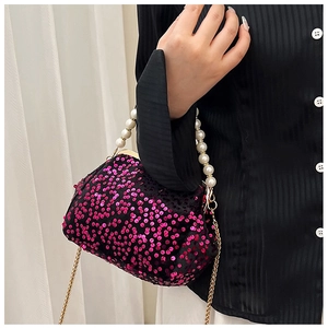 Detail of rose pink sequin clutch with pearl handle and golden chain on model