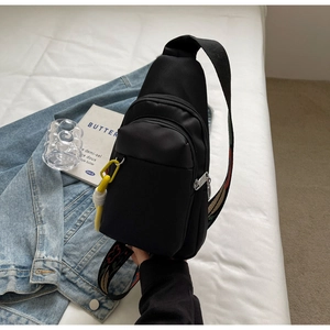 Minimalist black nylon crossbody bag with colorful ethnic jacquard strap on white bedding