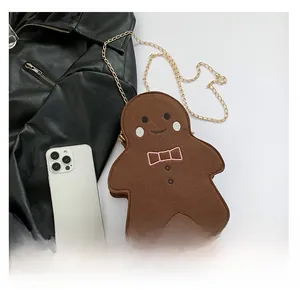 Detail der Lebkuchenmann-Filztasche mit goldener Kette neben einem Smartphone für den Maßstab